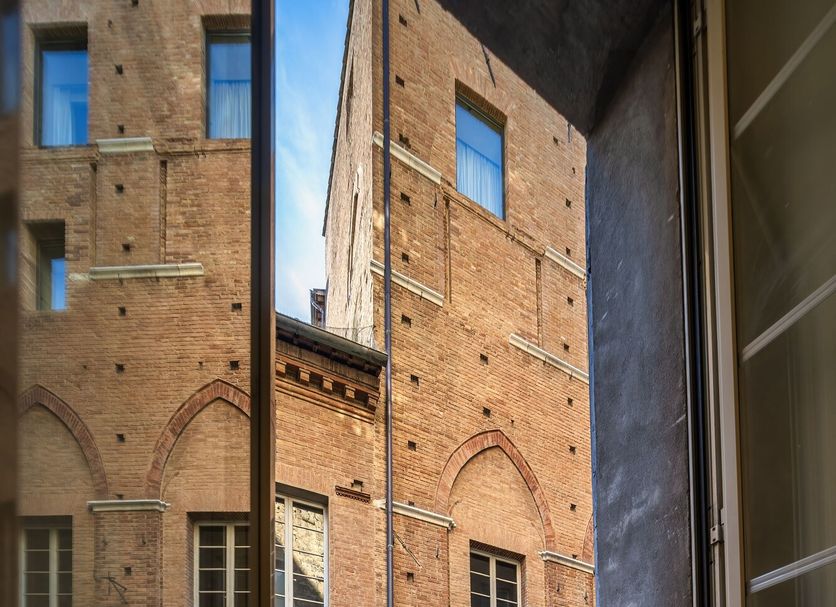 Piccolo Hotel Etruria in Siena courtyard view through open doorway with tables and chairs