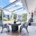 Mineralienhotel Natznerhof in Natz-Schabs: glass sunroom with stone table, chairs, and garden view