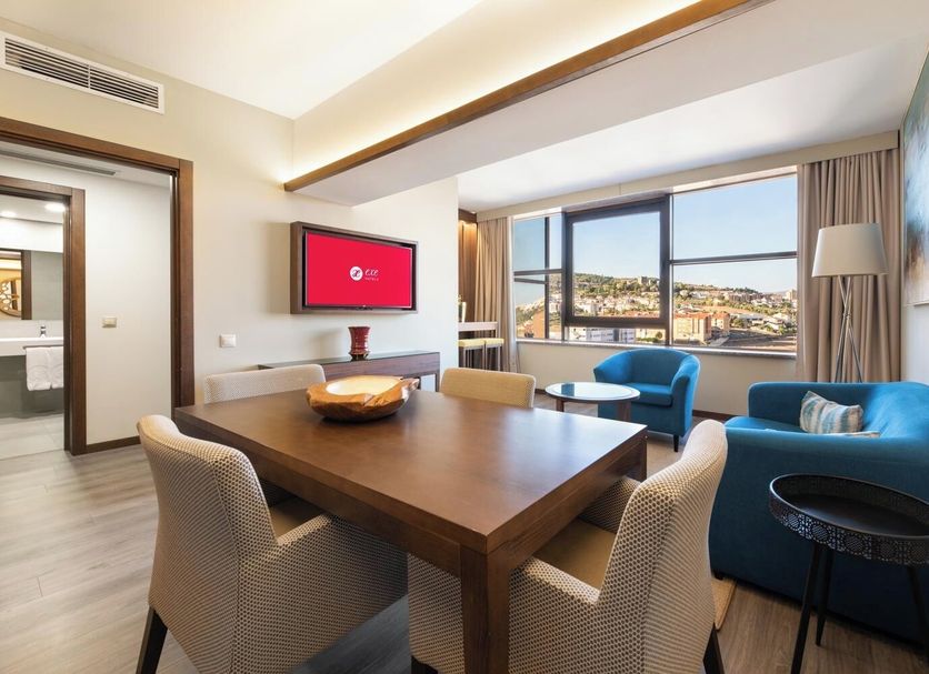 Exe São Lázaro in Bragança suite with dining area, blue seating and city view through large windows