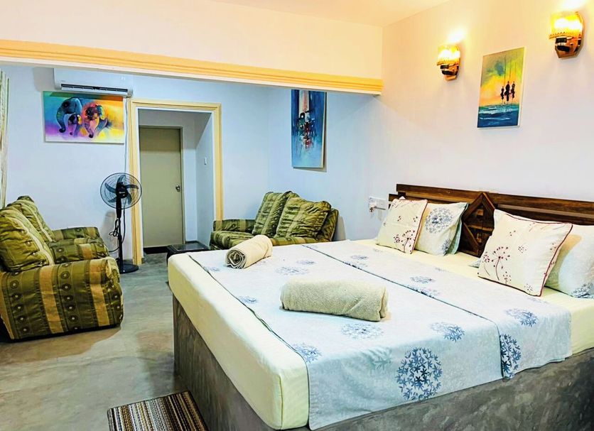 Arcadia Resort Hikkaduwa guest room with king bed, sofa seating, wall art and wall sconces