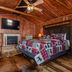 Log Cabin Inn in Eureka Springs rustic log cabin room with king bed, fireplace, wall TV and wood ceiling