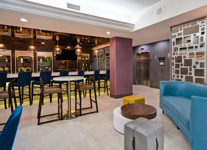 Hampton Inn New York-JFK in Queens lobby lounge with bar seating, elevator and blue sofa
