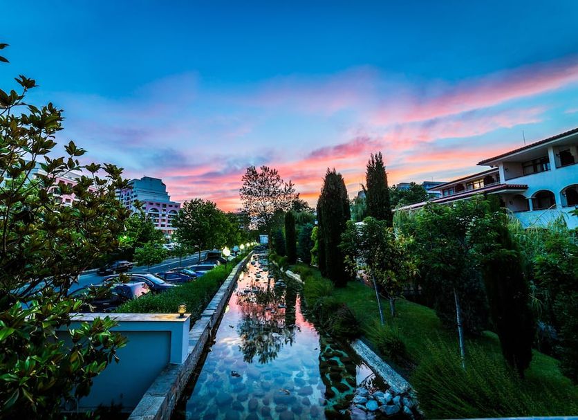 Royal Palace Helena Park in Sunny Beach with a long reflective pool at sunset and lush gardens