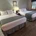 Harbor Light Inn in Ellison Bay guest room with two double beds, lamps, and wood flooring