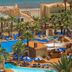 Playasol in Roquetas de Mar with palm-lined pool, blue loungers, and sea views