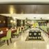 Grand Kuta Hotel and Residence in Kuta restaurant with neatly set dining tables and green chairs
