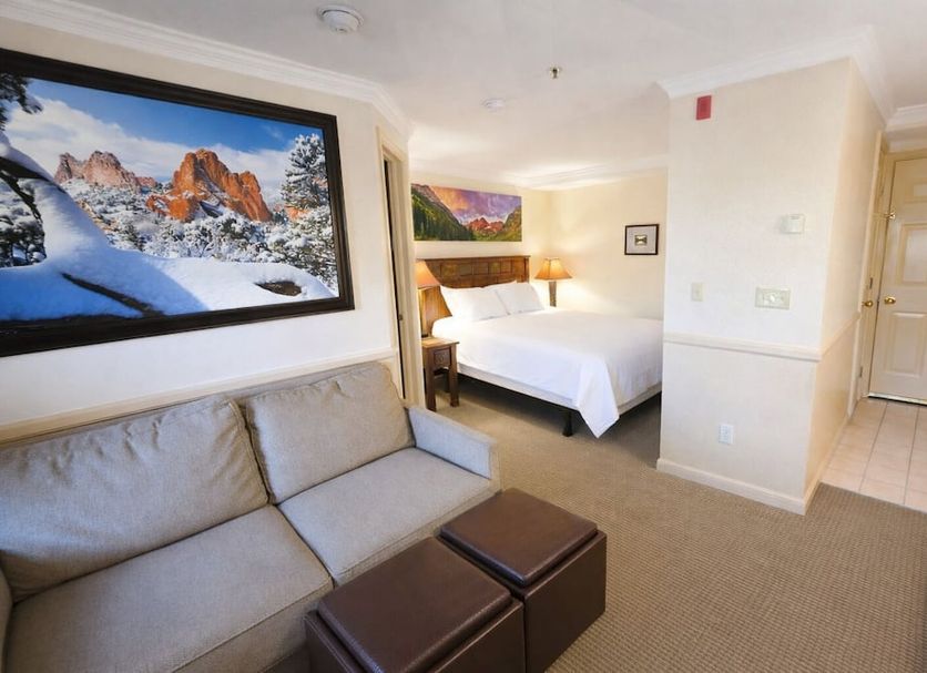 The Historic Crags Lodge in Estes Park guest room with bed, sofa, and mountain artwork