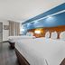 Baymont by Wyndham Tuscaloosa room with two beds, blue accent wall, desk and chair