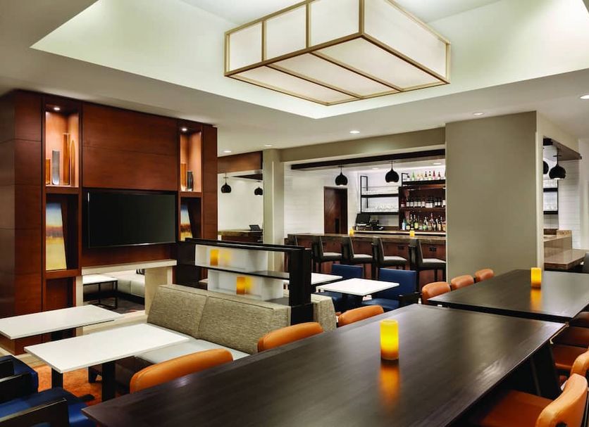 Hyatt House Denver Airport lounge with bar seating, booths, and a mounted TV in Denver
