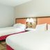Hampton Inn Garden City guest room with two white beds and orange headboards