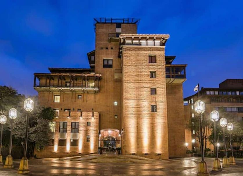 Travelers Condominio Plenitud in Bogotá, warmly lit brick hotel exterior at dusk