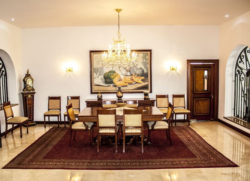 Hotel Boutique Villa Casuarinas in Cali dining room with chandelier, long table, chairs and large framed art