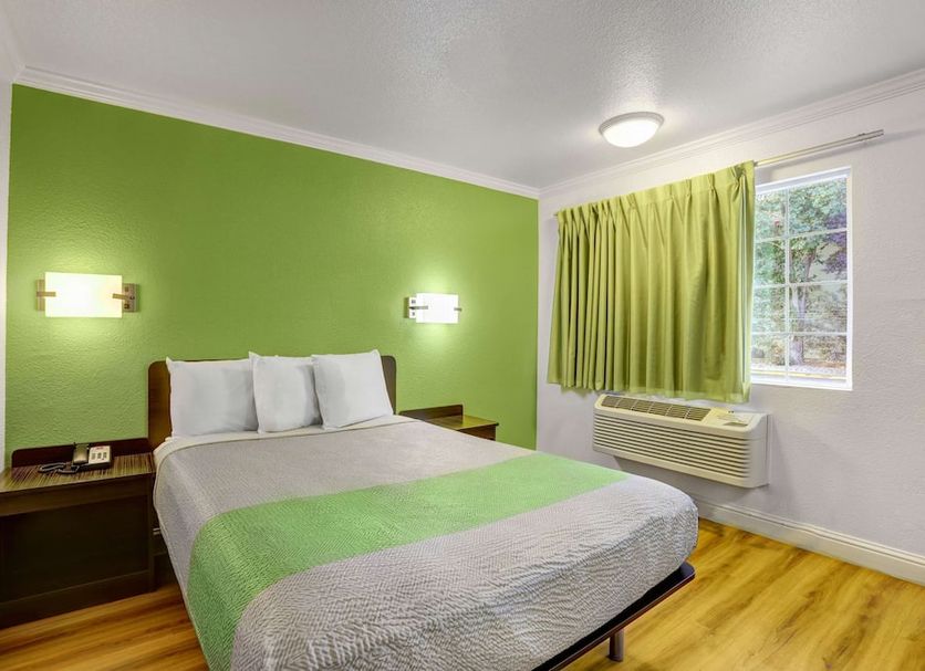 Motel 6 King City CA guest room with bed, green accent wall, window, and wood floor
