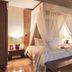 Plataran Ubud Hotel And Spa bedroom with canopy bed and sliding doors to a garden patio in Denpasar