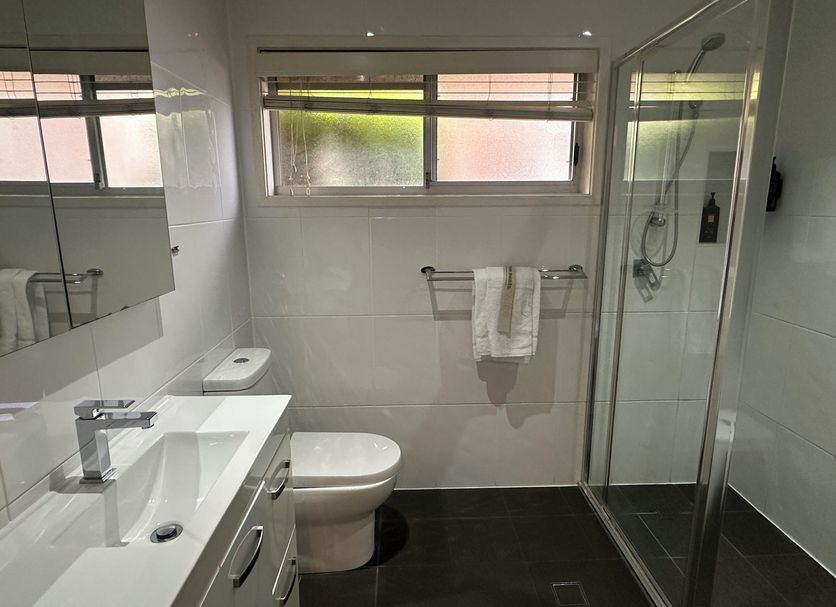 The Oaks Hotel Motel Wollongong bathroom with shower, toilet, sink and window