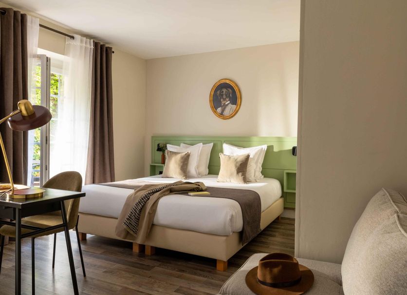 Hôtel Le Pré Galoffre guest room in Nimes with double bed, desk, window and seating area