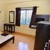 MM Tourist Home in Kāsaragod: simple guest room with bed, desk, mirror, and window with curtains