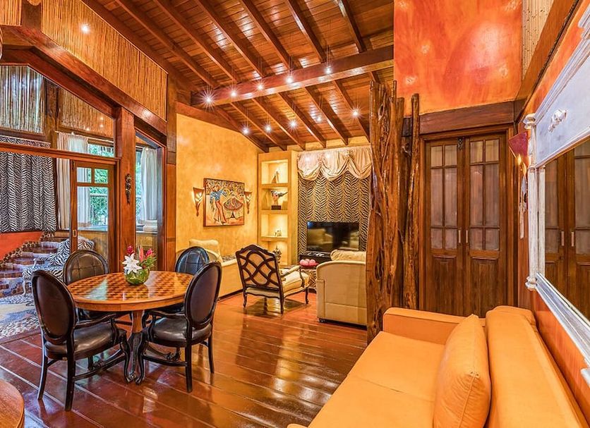 DPNY Beach Hotel in Ilhabela lounge with wood-paneled ceiling, dining table, sofa, and garden view
