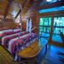 A Cabin In The Woods in Pigeon Forge bedroom with log walls, rustic bed, and sliding glass door to deck