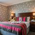 Coed-Y-Mwstwr Hotel in Bridgend guest room with patterned wallpaper, king bed, and window seating