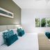 Mantra Portsea Port Douglas guest room with king bed, window view, and TV cabinet