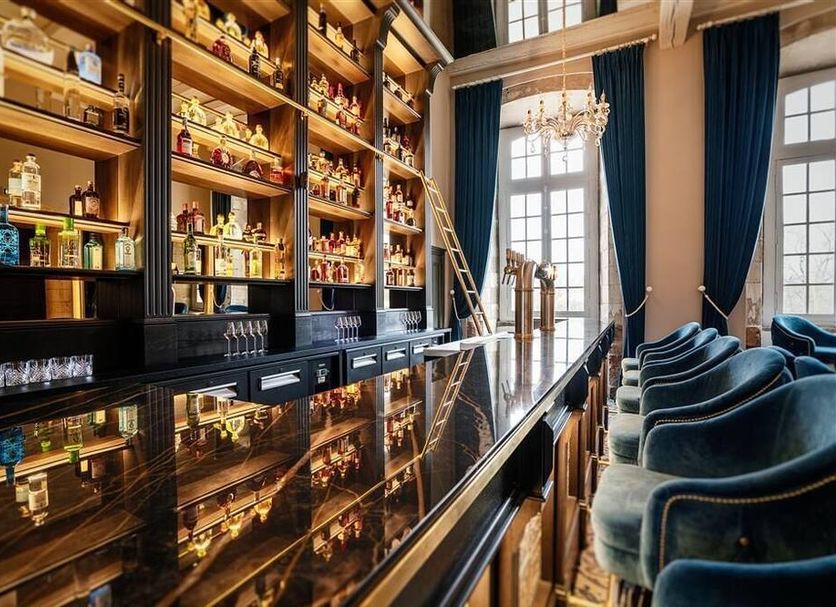 Abbaye De Villeneuve in Les Sorinières, elegant bar lounge with backlit shelves and tall windows
