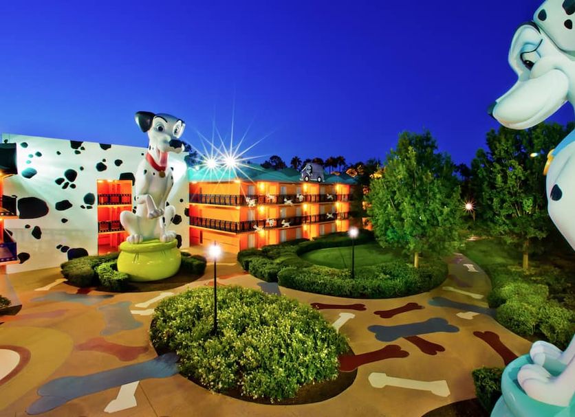 Disney's All-Star Movies Resort in Bay Lake with giant Dalmatian statues and lit courtyard at dusk