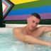 Coqui del Mar Guesthouse in San Juan with a man relaxing in a hot tub beneath a rainbow mural.