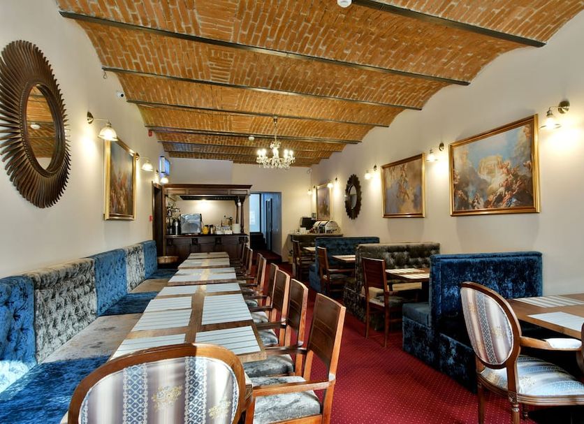 Safrano Palace in Braşov dining room with long tables, blue seating, and brick vaulted ceiling
