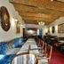 Safrano Palace in Braşov dining room with long tables, blue seating, and brick vaulted ceiling
