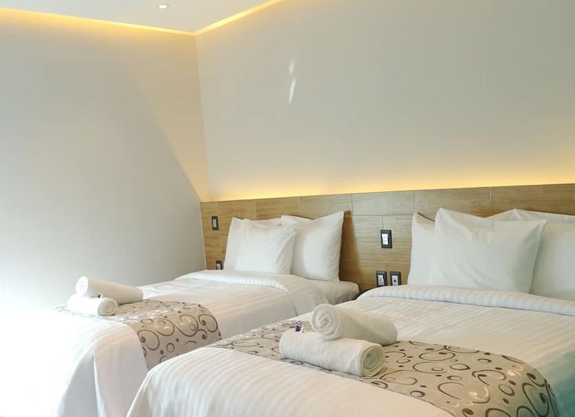 Hotel Kavia Plus in Cancún: bright twin beds with white linens and warm headboard lighting