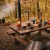 Postcard Cabins Asheboro picnic table setup with camp chairs in a wooded outdoor setting