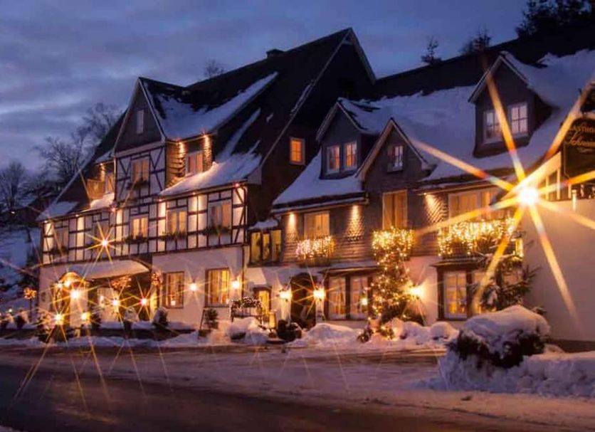 Landgasthof Schneider, Westfeld in Schmallenberg, snow-covered hotel exterior at dusk with warm lights