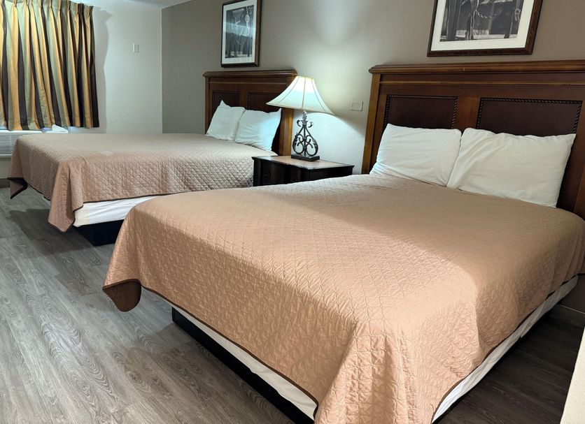 Island Inn in Grand Island guest room with two beds, bedside lamp, framed wall art and window curtains