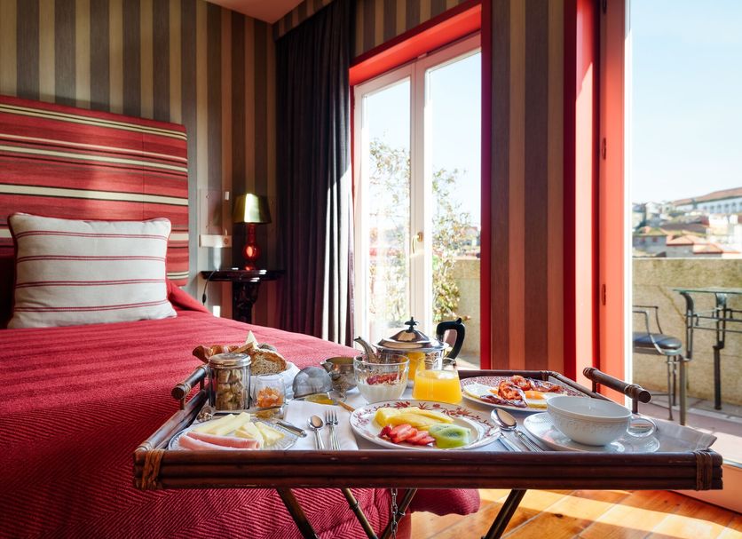 M Maison Particulière Porto guest room with breakfast tray by a balcony door and city view