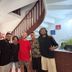 Guests posing in Global Hostel Sao Paulo lobby beside a curved staircase and brick counter.