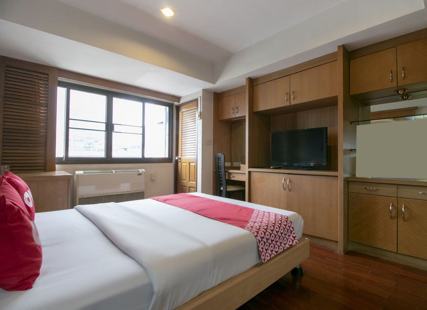 Hotel Win Long Bangkok guest room with bed, TV cabinet, window and wood cabinetry