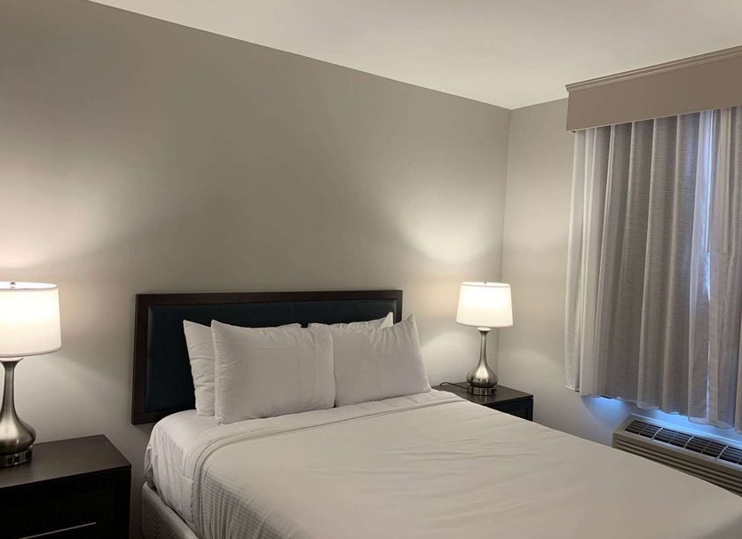Wingate By Wyndham Jfk Airport / Far Rockaway guest room with queen bed, lamps and window in Queens
