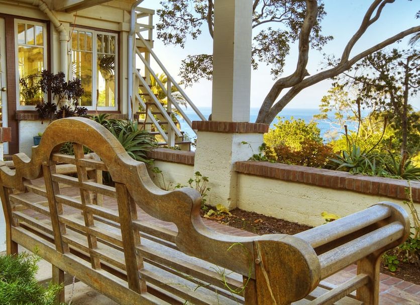 Banning House Lodge in Avalon: ocean-view patio with wooden bench, stairs, and tree-framed garden