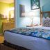 Barefoot Suites Kissimmee guest room with king bed, colorful bedding, and adjoining bathroom