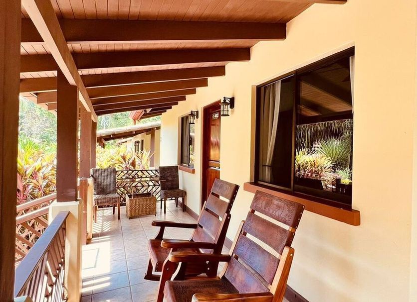 La Foresta Nature Resort in Quepos with a covered balcony corridor and wooden chairs overlooking tropical greenery