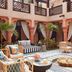 Jumeirah Dar Al Masyaf Dubai courtyard lounge with wicker seating, palm plants, and patterned rugs