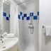 Appart'City Classic Thonon Les Bains bathroom with shower, sink, mirror and blue tile accents
