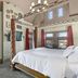 Patterson Inn Denver bedroom with four-poster bed, brick fireplace and city views through tall windows