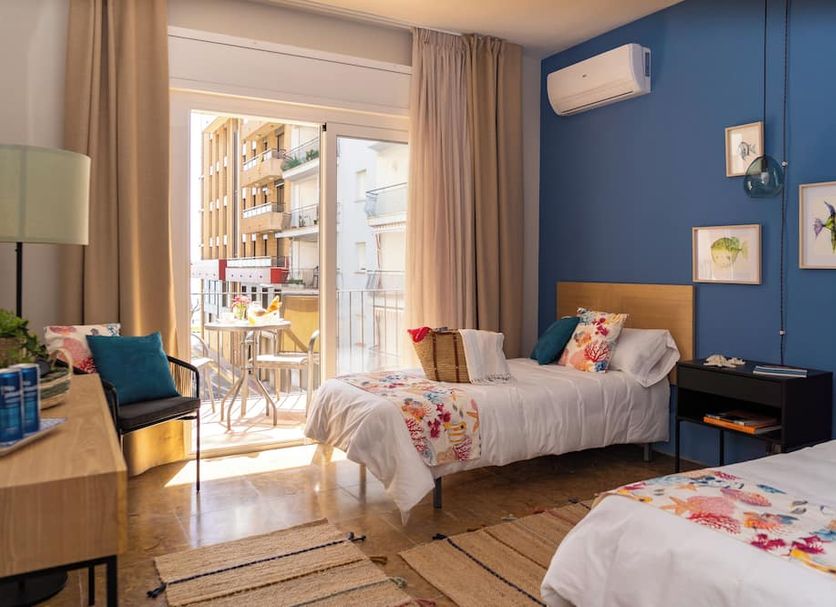 Hotel Aubi in Palamós guest room with twin beds, blue accent wall, and balcony door open to street view