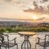 Hotel & Spa Der Steirerhof in Bad Waltersdorf with terrace chairs and table overlooking a sunset valley