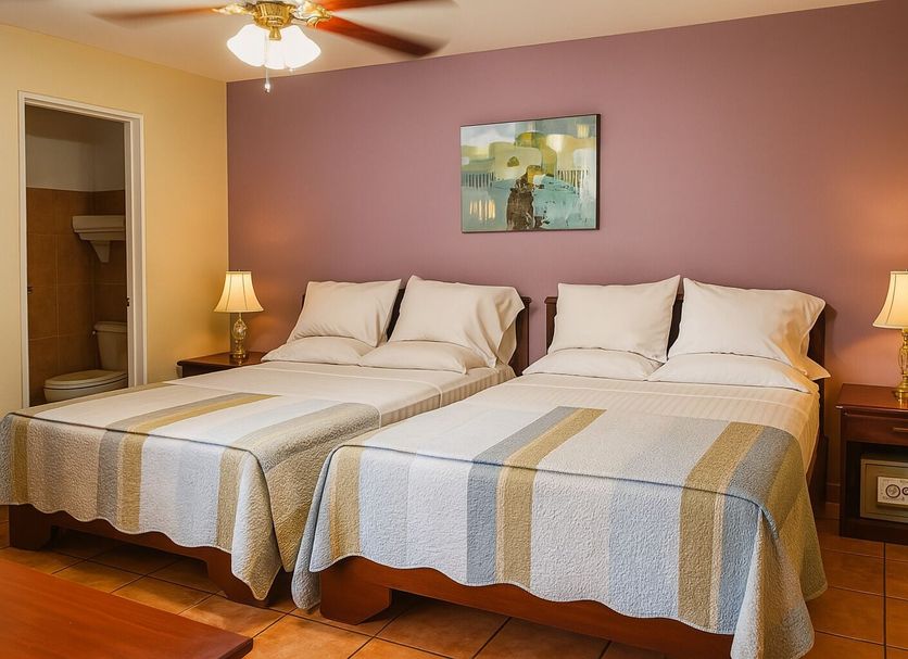 Hotel Puerta del Sol - San Jose Airport room with two double beds and purple accent wall in San José