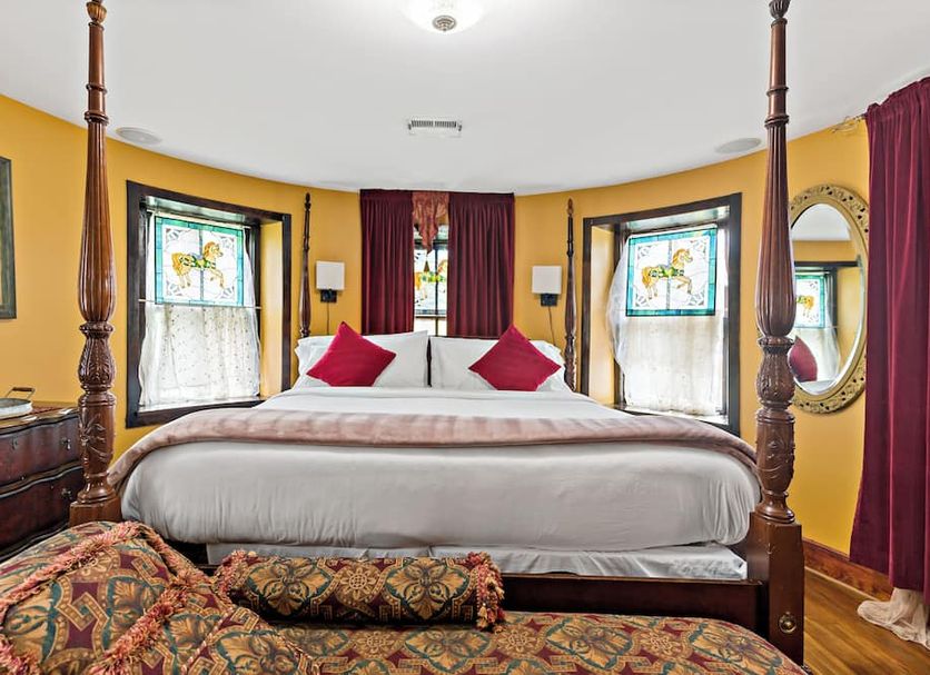 Stone Manor Boutique Inn in Lovettsville bedroom with four-poster bed, bay windows, and colorful decor