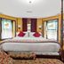 Stone Manor Boutique Inn in Lovettsville bedroom with four-poster bed, bay windows, and colorful decor