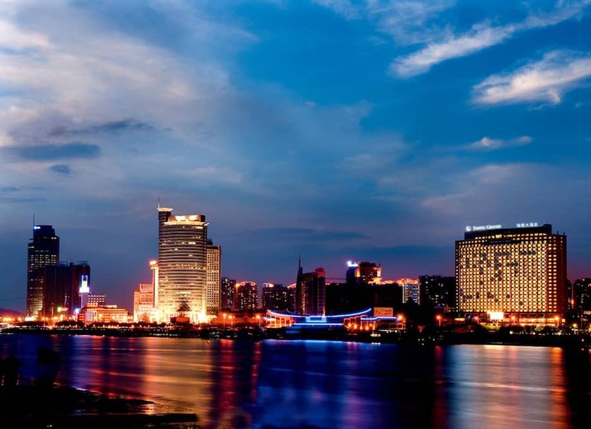 Swiss Grand Xiamen skyline view over Xiamen harbor at dusk with city lights reflecting on water